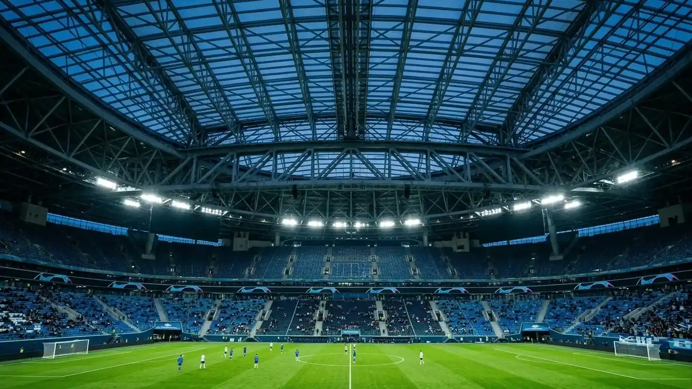 A modern stadium with a closed roof lit for a night soccer match