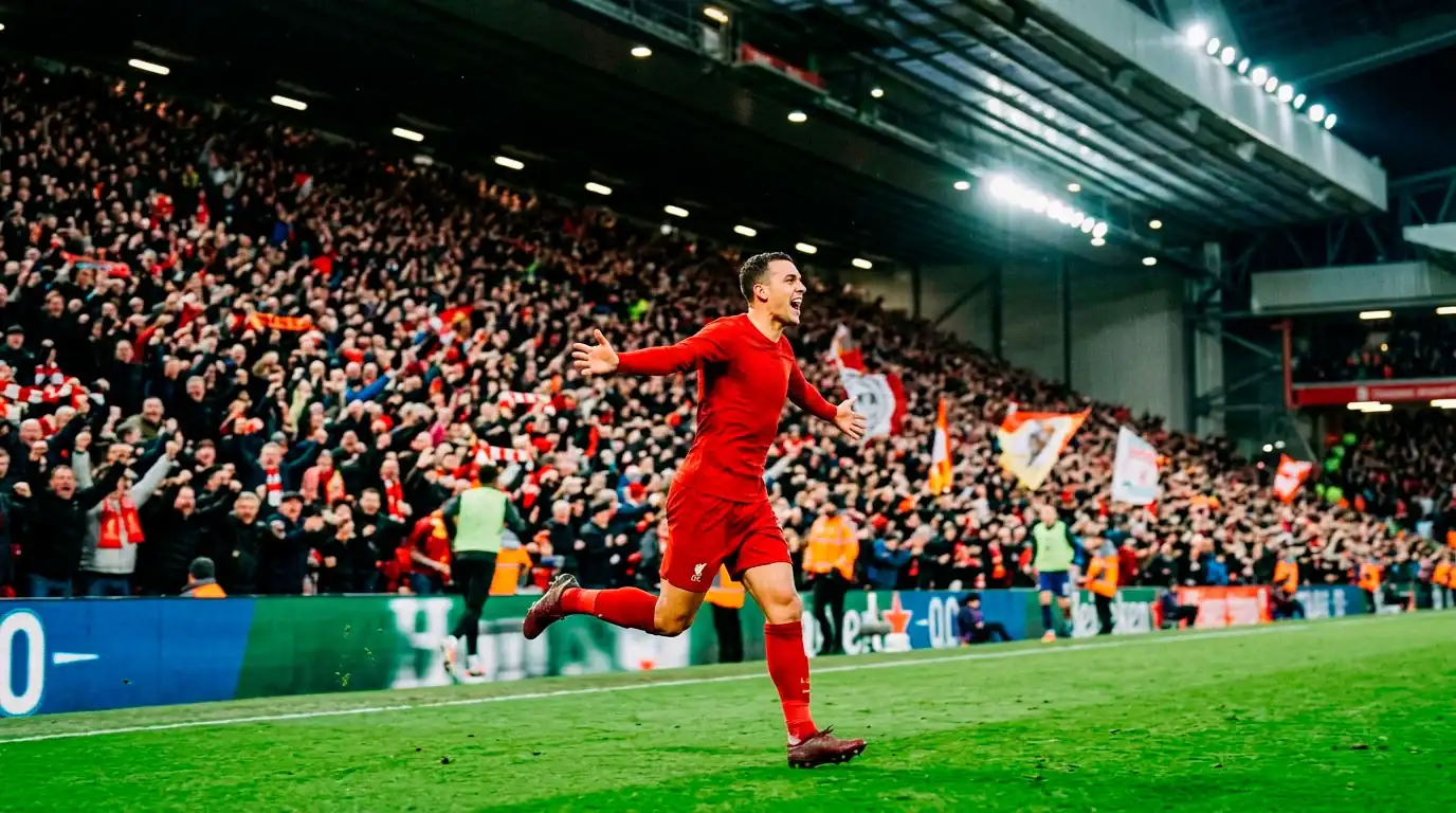 A soccer striker in red celebrating a goal with arms outstretched in front of a roaring home crowd